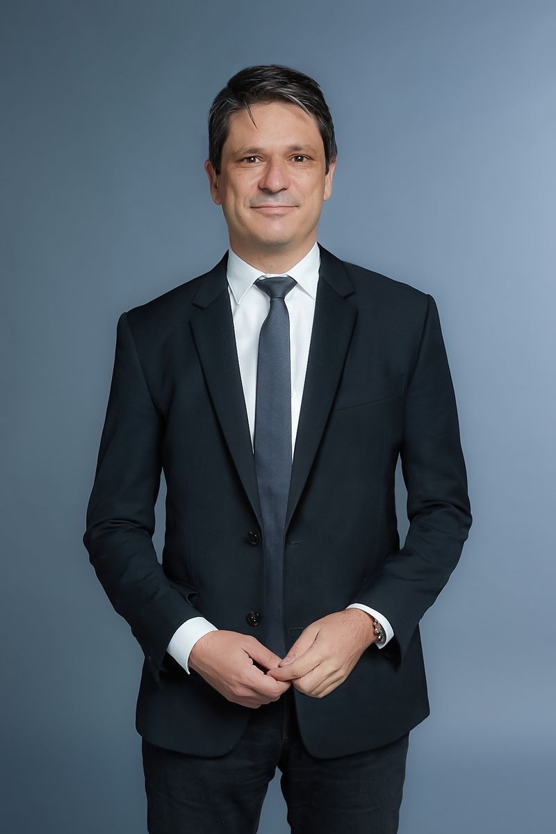 Eric Delattre standing, in a dark suit